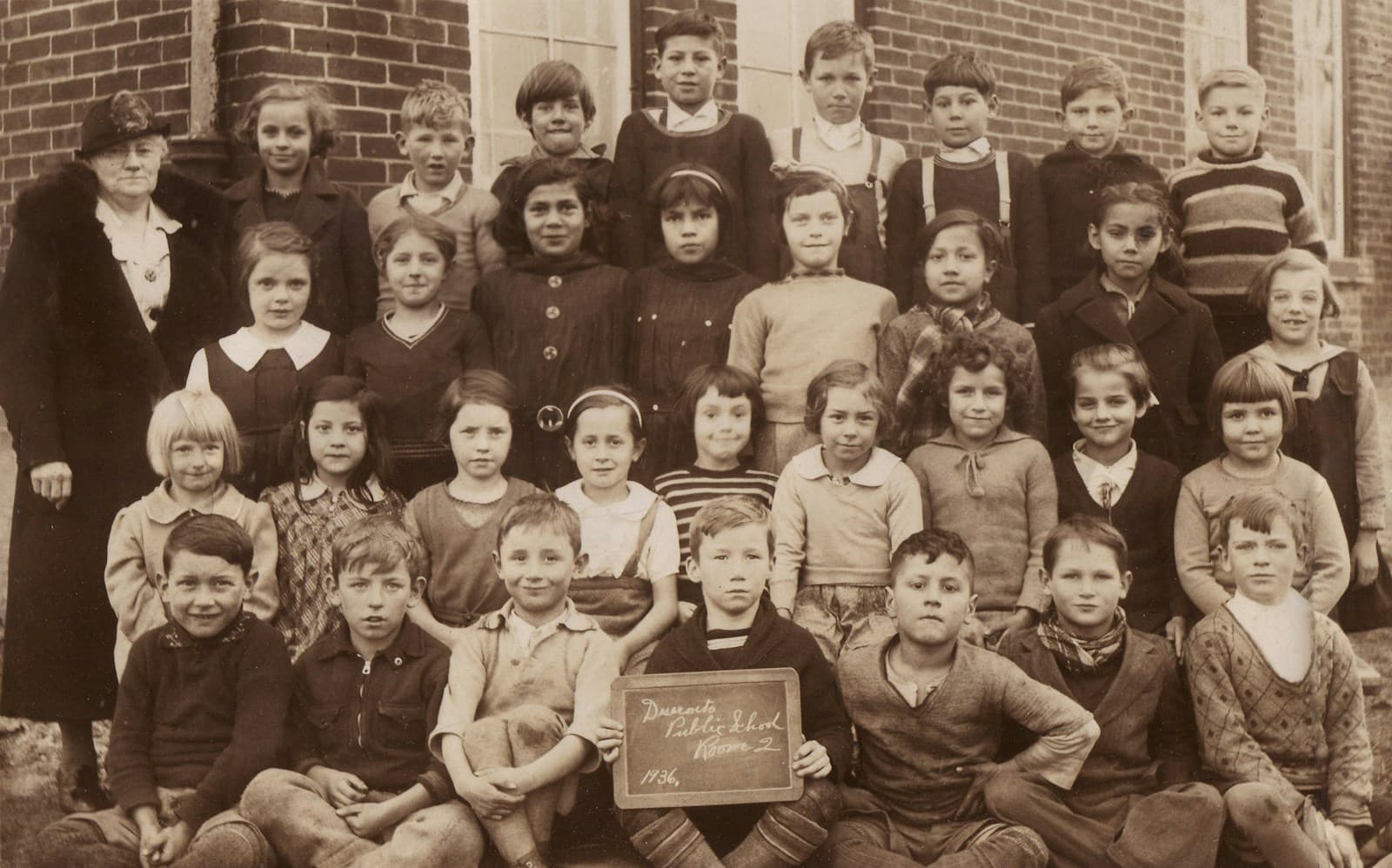 Foto di classe d'epoca di alunni con la loro maestra